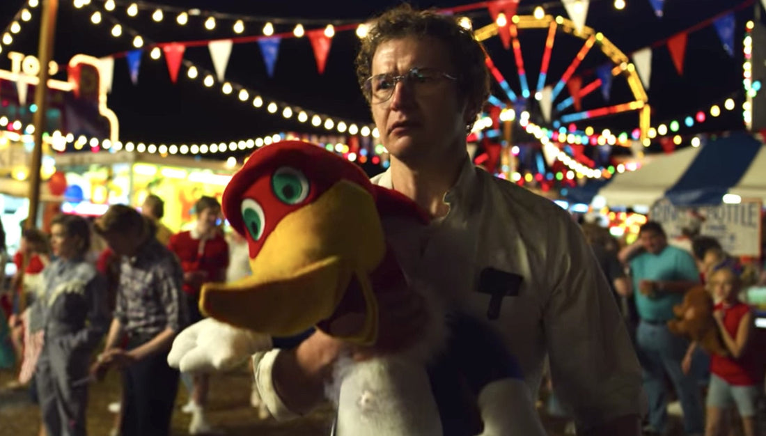 Alexei at the fair, a plush bird in his arms, the Ferris wheel behind him.