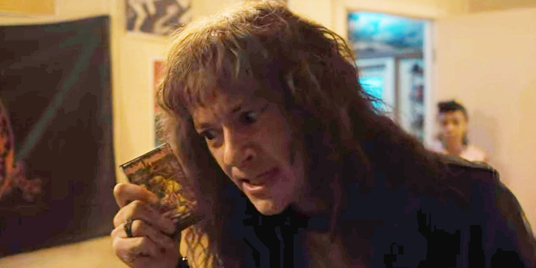Eddie Munson holds up an Iron Maiden cassette, Piece of Mind, in his bedroom